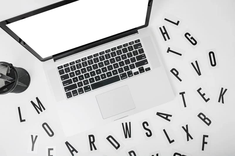 Ordinateur portable entouré de lettres, illustrant l’importance d’un contenu clair pour un site WordPress optimisé SEO